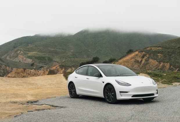 white sedan parked beside mountain during daytime