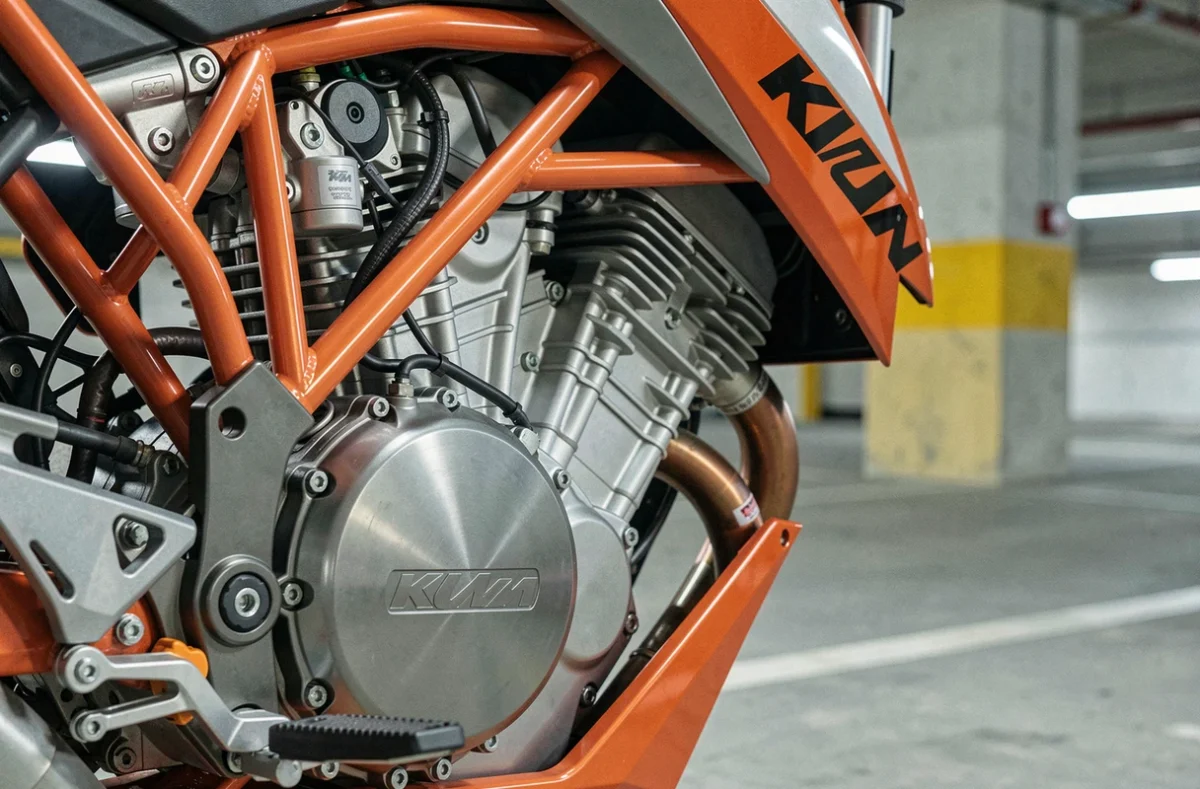 Détail du moteur monocylindre et du cadre treillis de la KTM Duke 125 2026 photographié en parking urbain souterrain, texture mécanique et finitions engineering en gros plan