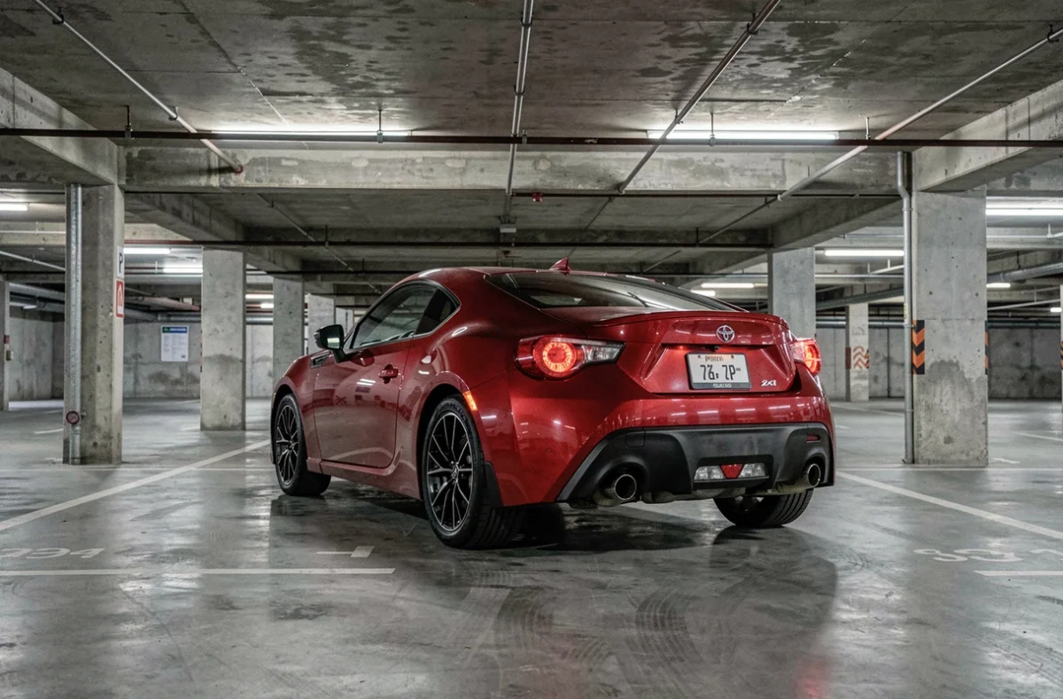 Toyota 86 rouge vue de trois quarts arrière dans un parking urbain souterrain en béton