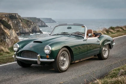 Triumph TR3 vert British Racing Green sur route côtière sinueuse, vue trois quarts avant